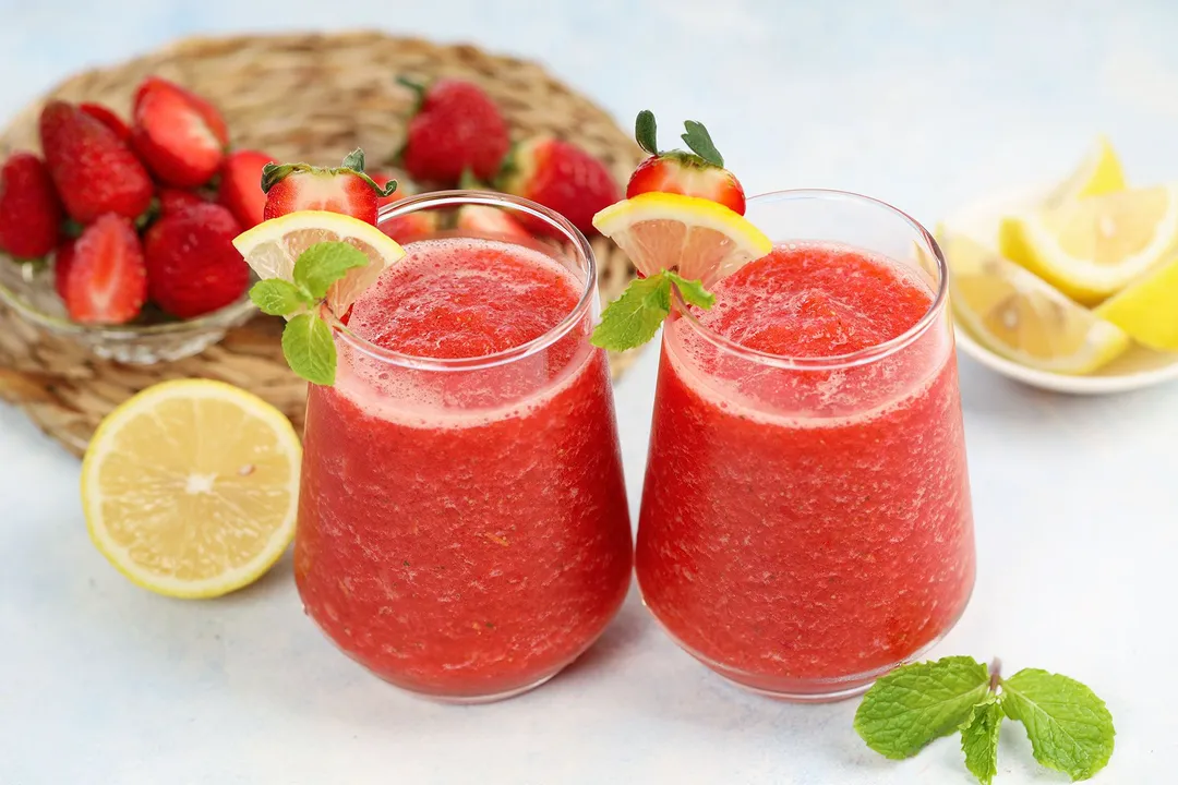 two glasses of strawberry lemonade smoothie decorated with half lemon, strawberries