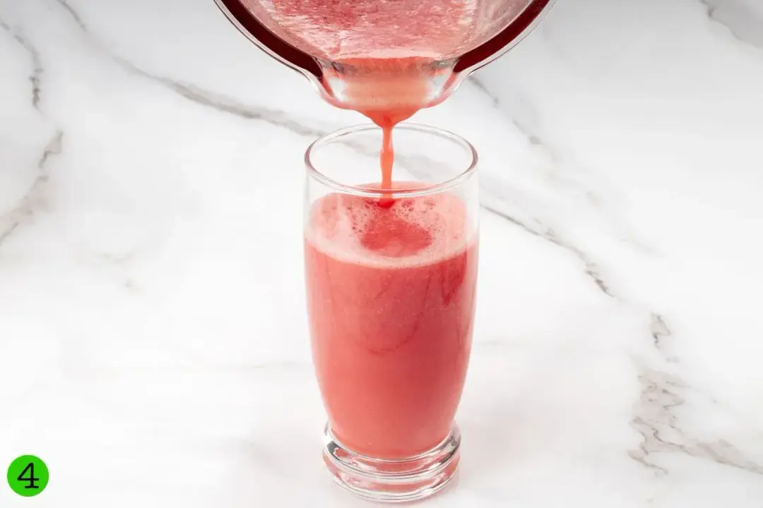 Watermelon smoothie being poured from a blender into a glass