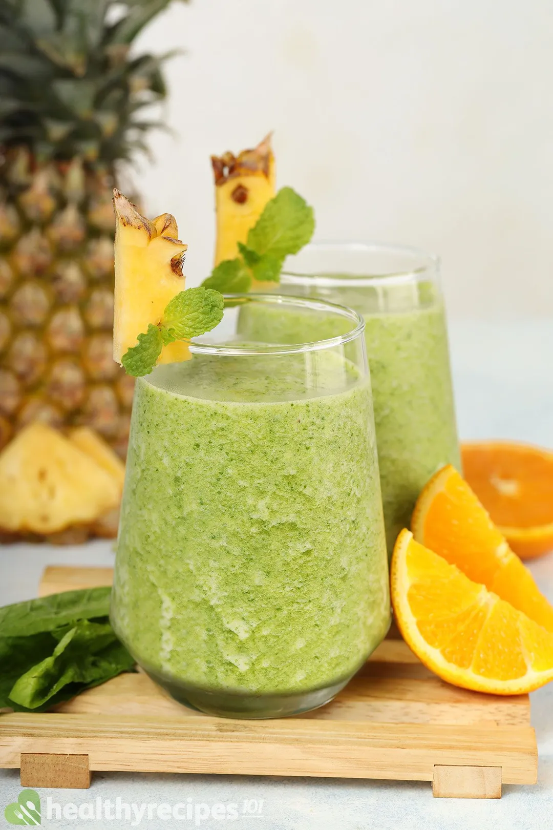 two glasses of pineapple spinach smoothie on a tray