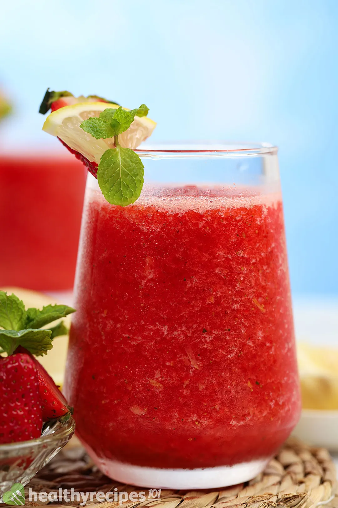 a glass of strawberry lemonade smoothie, decorated with lemon slice, mint leaves and strawberries
