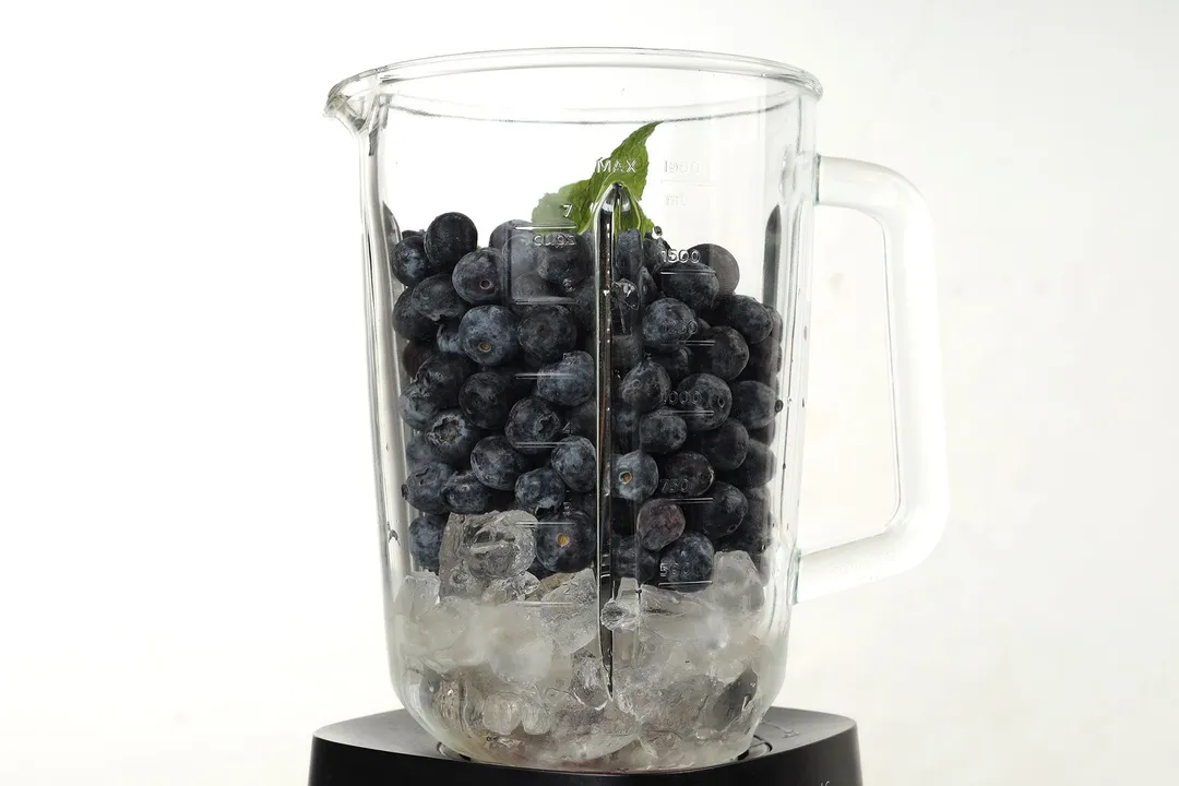 a blender pitcher full of blueberries and ice