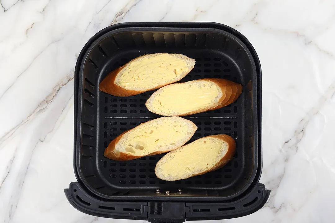 four bread slices in an air fryer basket