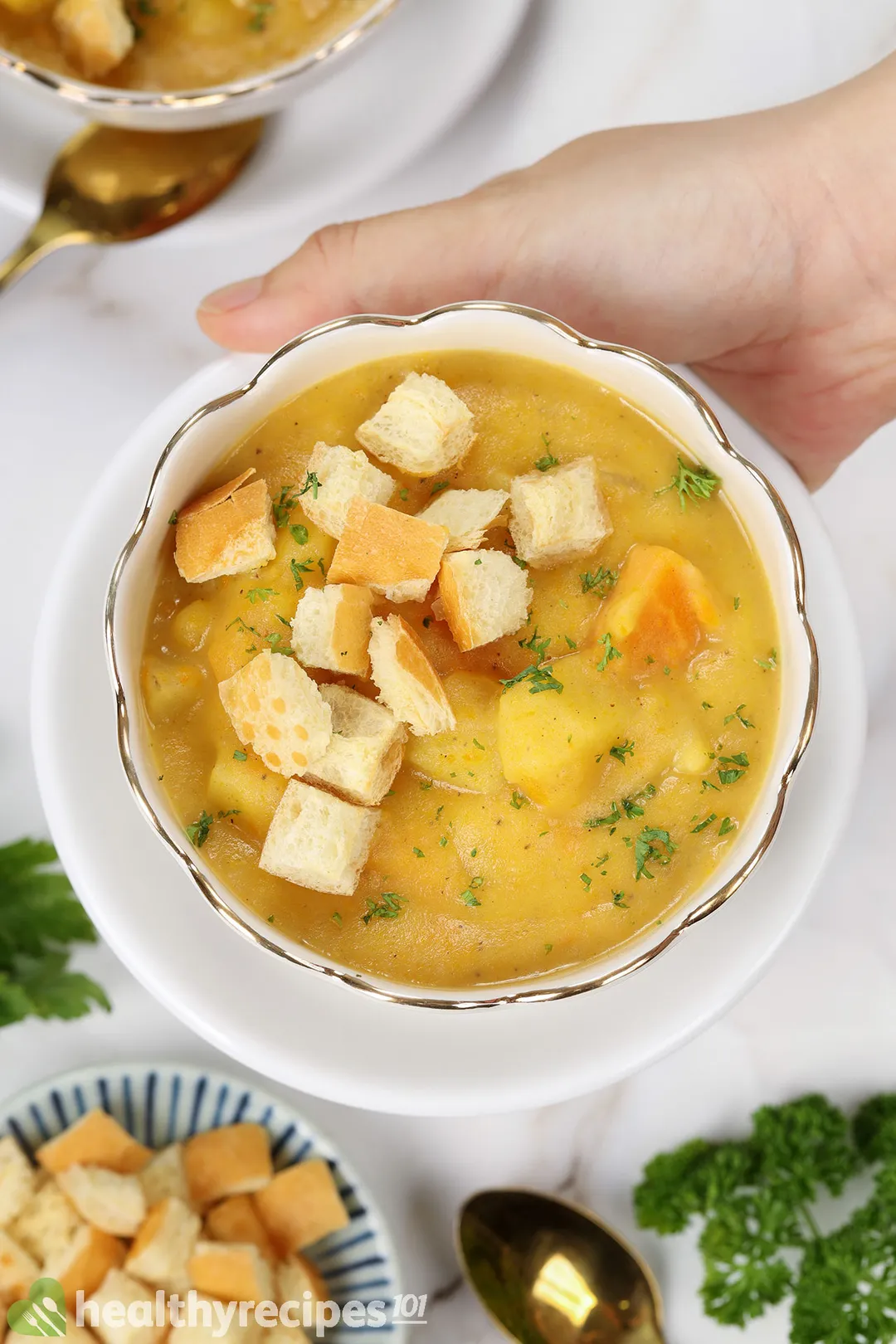 a hand holding a bowl of potato soup