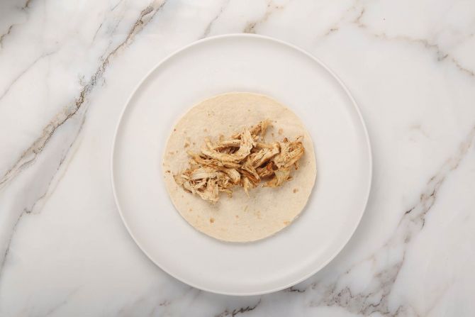 Step 5: Spoon some of the shredded chicken onto the tortilla.