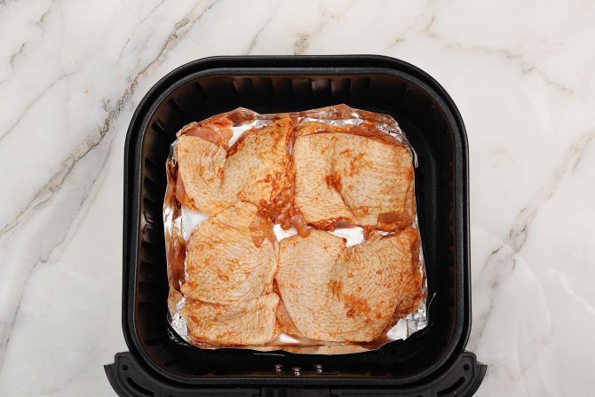 step 2: Make a baking tray out of foil, and place in the air fryer. Add the chicken and cook.