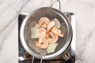 Step 3: Remove the poached shrimps with a mesh sieve to drain water and discard the yellow onion.